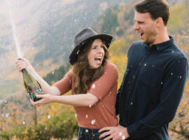 engaged couple popping champagne in Colorado mountains