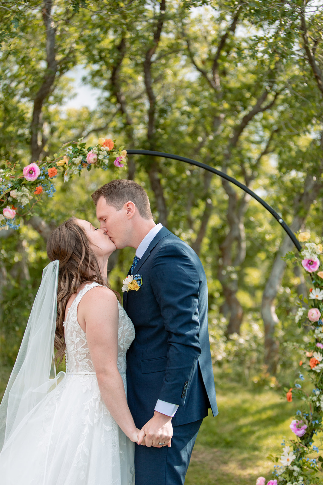 first kiss in front of colorful wedding ceremony altar