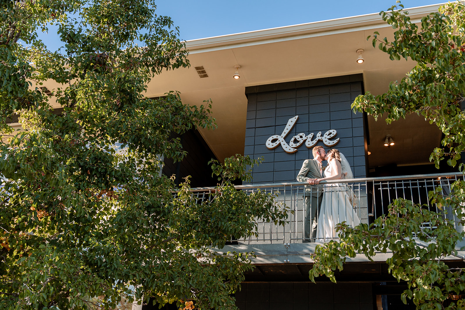 wedding photo with husband and wife on a balcony in front of "love" sign